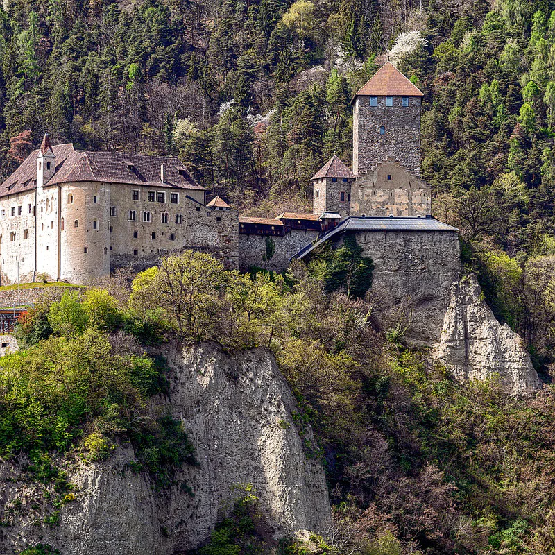 Castel Tirolo surrounded by golden vineyards and autumn woods in Trentino-Alto Adige
