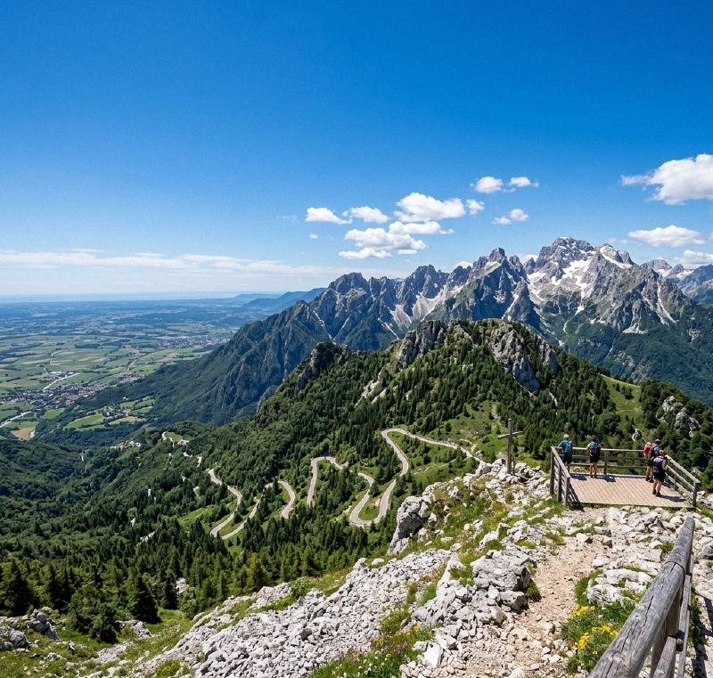 Panoramic view from Monte Tremol in Piancavallo, showing rugged peaks and the distant Friuli plain.